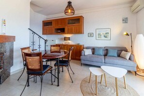 Ein modernes Wohnzimmer mit Essbereich, ausgestattet mit einem Holztisch, Stühlen, einer Couch und einem Couchtisch.