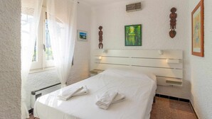 Una habitació d'hotel amb un llit, una finestra amb cortines, un quadre i una prestatgeria penjada a la paret.