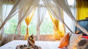 A room with a bed, curtains, a lamp, and a view of greenery outside. - Selini Hills (Labuan Bajo)