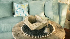A round wooden table with a decorative bowl and a metal object, placed on a woven mat. - Selini Hills (Labuan Bajo)