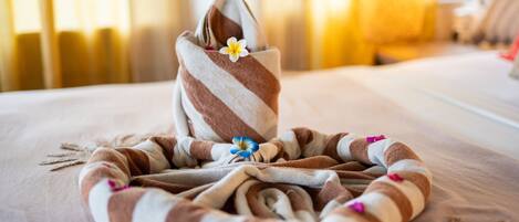 Una toalla bien ordenada con una flor sobre una cama en una habitación de hotel.
