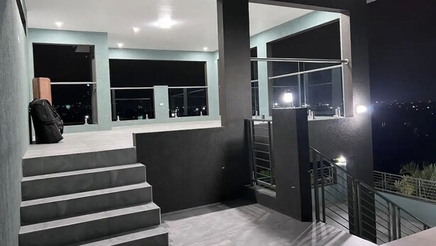 A modern staircase leading to a balcony with a city view at night. - Luxury one bed room apartment with AC, roof top pool, WIFI located in Kingston. (Kingston)