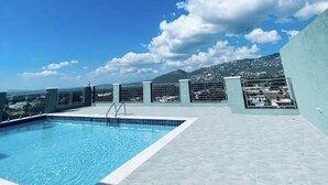 A rooftop pool with a clear view of the cityscape and mountains in the background. - Luxury one bed room apartment with AC, roof top pool, WIFI located in Kingston. (Kingston)