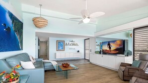 Un vaste espace de vie au design moderne, comprenant un canapé, une table basse, un téléviseur et un ventilateur de plafond.