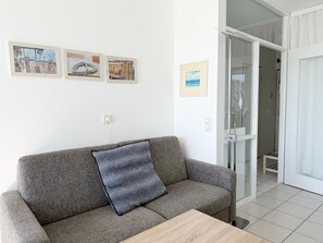 Una sala de estar con un sofá gris, una mesa de centro de madera y tres cuadros en la pared.