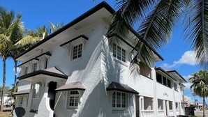 A two-story white building with a balcony, a satellite dish, and a driveway. - Sans Souci Apartments (Ingham)