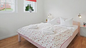 Un dormitorio con cama, dos mesitas de noche, un ventanal con vistas y una mesita de noche con lámpara.