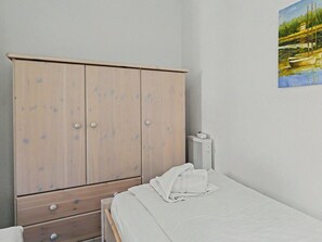 A bedroom with a bed, a wooden wardrobe, and a radiator.