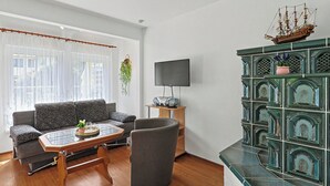Un salón con sofá, una mesa de centro, televisor y un modelo decorativo de barco.