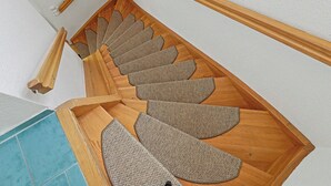 Una escalera de madera con un suelo alfombrado y con textura.