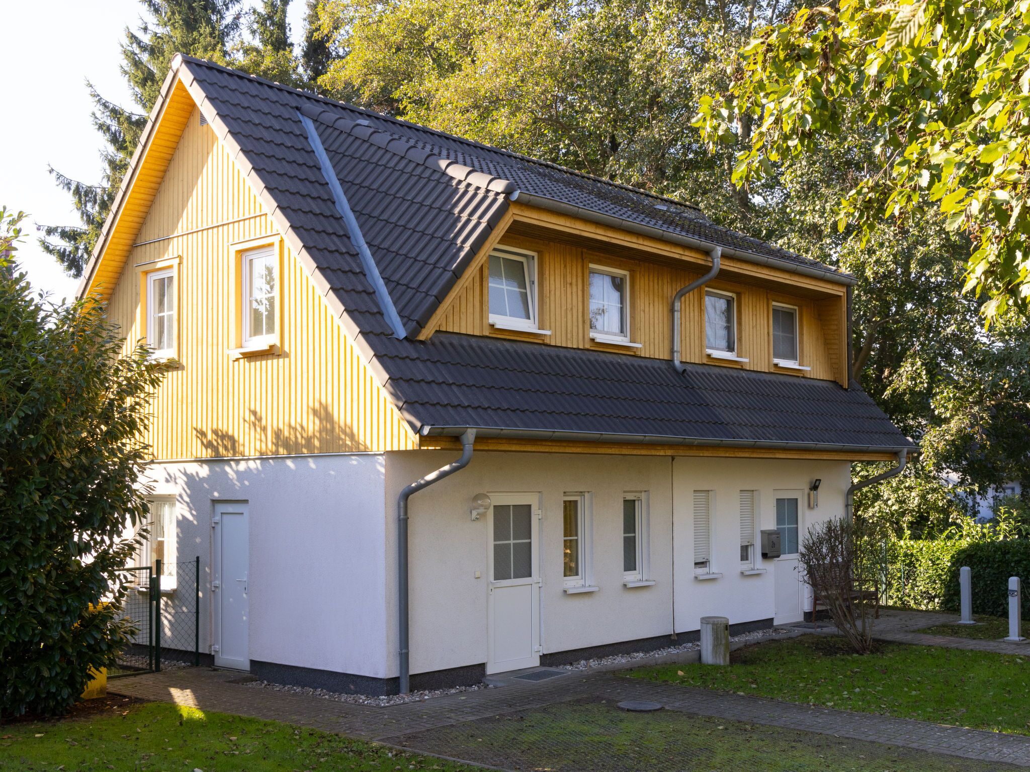 A two-story house with a sloped roof, wooden siding, and a white lower section.