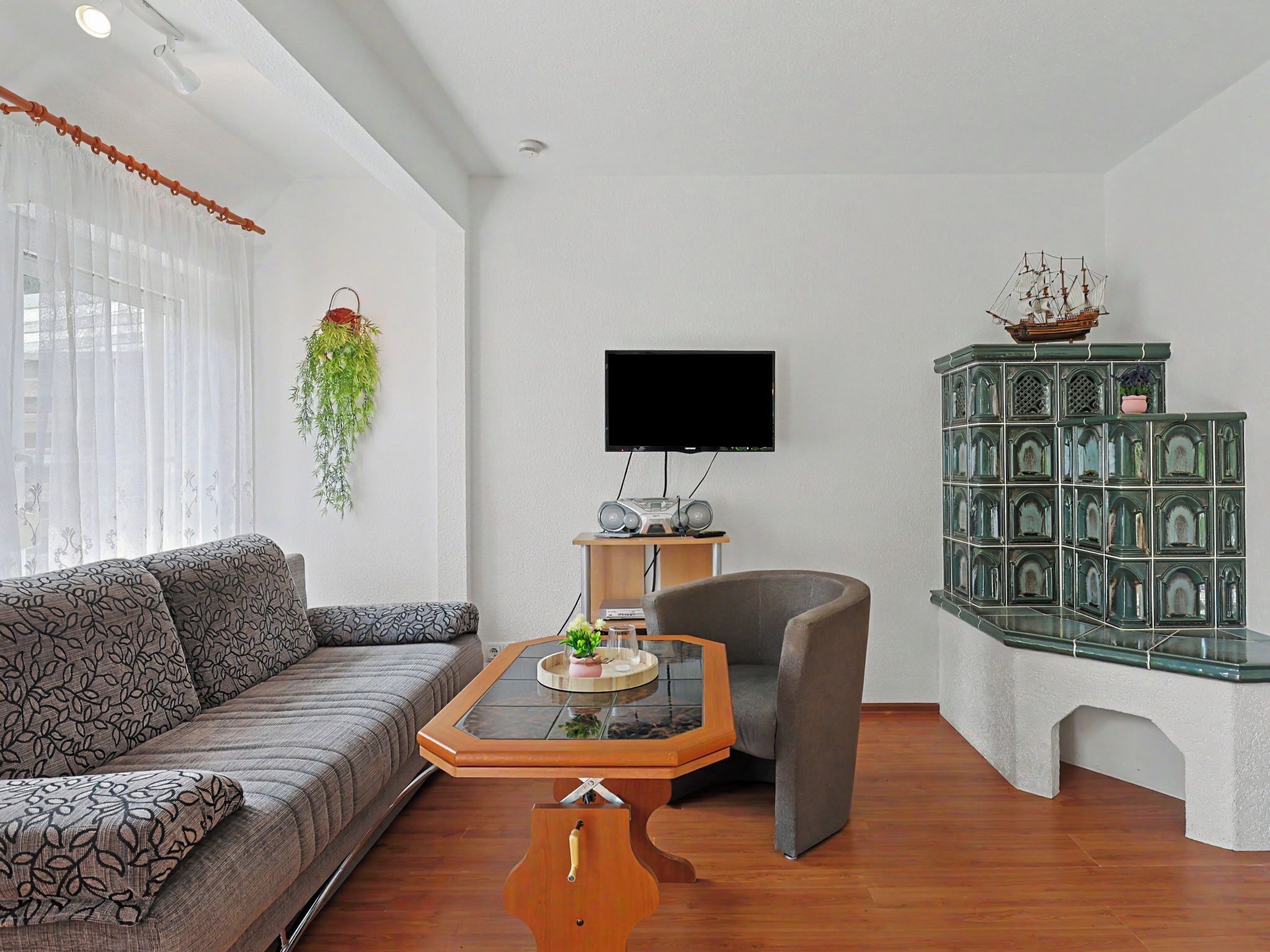 Een woonkamer met een bank, een salontafel, een televisie, een radio en een decor kast.