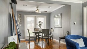A dining area with a table and chairs, a ceiling fan, and a blue armchair.