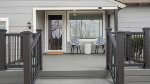 A house with a porch, two chairs, and a small table.