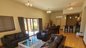 A spacious living room with a leather sofa, a glass coffee table, and a dining area with wooden chairs. - Find your stay peaceful and comfortable with luxury. Kids friendly (Scarborough)
