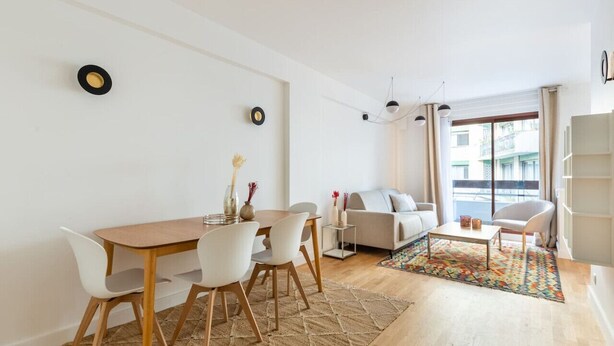 A modern living room with a dining area, a sofa, a coffee table, and a patterned rug. - Passy - 1 chambre - 2 lits (Paris)