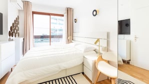 A modern bedroom with a large bed, bedside tables, a chair, and a TV mounted on the wall. - Passy - 1 chambre - 2 lits (Paris)