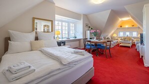 Un dormitorio con una cama grande, un escritorio y una zona de comedor.
