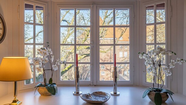 Una habitación con ventanas amplias, una lámpara y dos plantas en macetas.