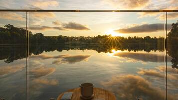 Relax in a serene outdoor seating area with a tranquil lake view, featuring a round table and two chairs.