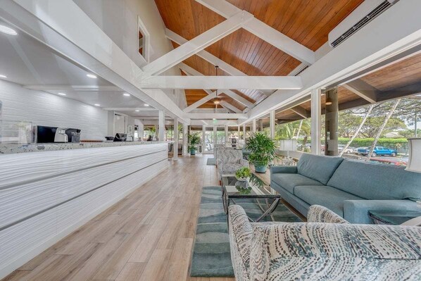Un espace intérieur spacieux avec un plafond en bois, un canapé, une table basse et un téléviseur.