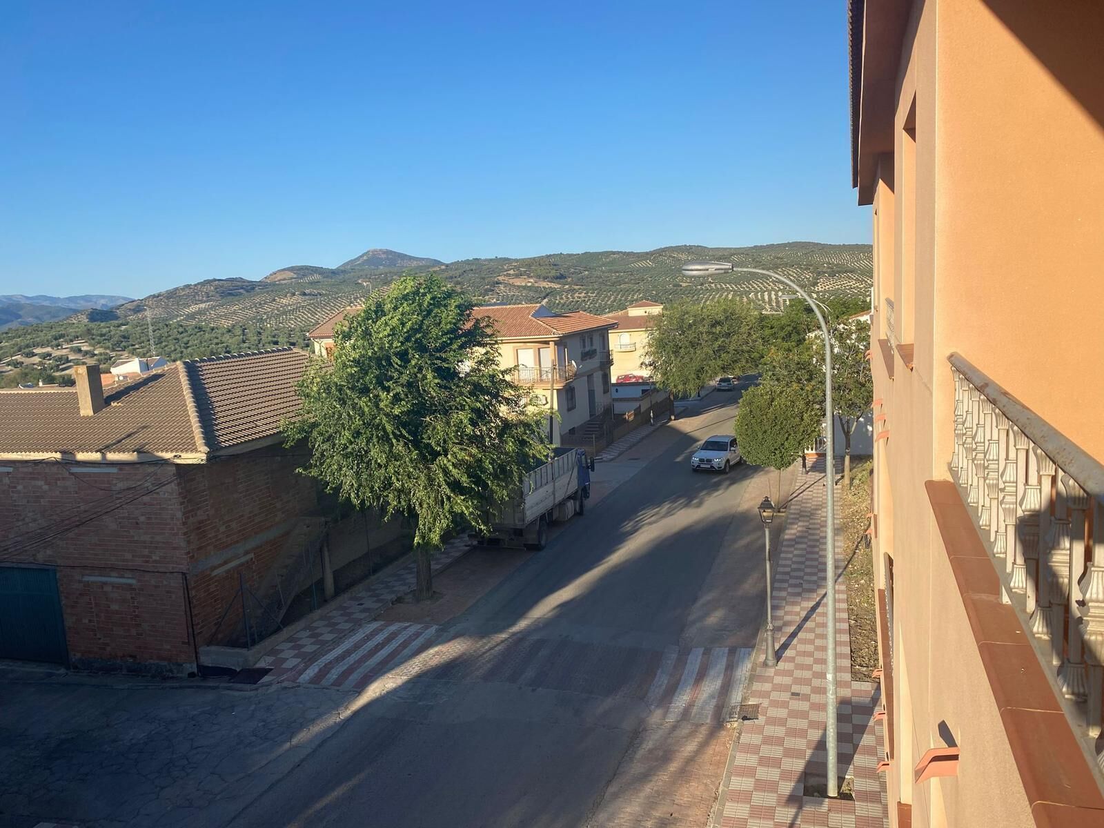 Vista de una calle con edificios, un árbol y cielo despejado.