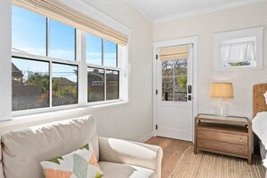 A bedroom with a large window, a door, a bedside table with a lamp, and a bed. - "Endless Summer" Home - stunning ocean views! (Santa Cruz)