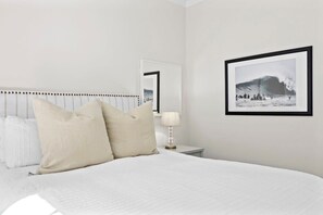 A bed with a headboard, a bedside table with a lamp, and a framed picture on the wall. - "Endless Summer" Home - stunning ocean views! (Santa Cruz)