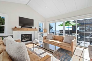 A spacious living room with a fireplace, a large flat-screen TV, and a comfortable sofa set.