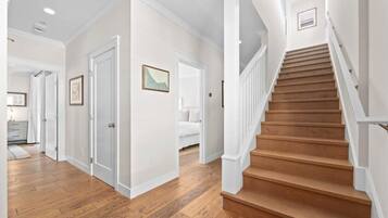 Una escalera de madera con barandillas blancas que conduce a un rellano con una puerta.