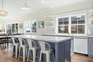 A modern kitchen with a central island, bar stools, and a view of the outdoors. - "Endless Summer" Home - stunning ocean views! (Santa Cruz)