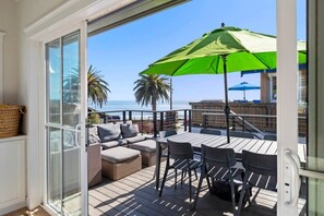 A deck with outdoor furniture, a green umbrella, and a view of the ocean. - "Endless Summer" Home - stunning ocean views! (Santa Cruz)