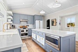 A modern kitchen with light blue cabinets, white countertops, and stainless steel appliances.