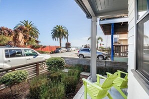 A hotel exterior with a covered outdoor seating area, a parking lot with cars, and palm trees in the background. - "Endless Summer" Home - stunning ocean views! (Santa Cruz)