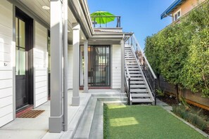 A modern house with a covered porch, a staircase, and a well-maintained lawn.