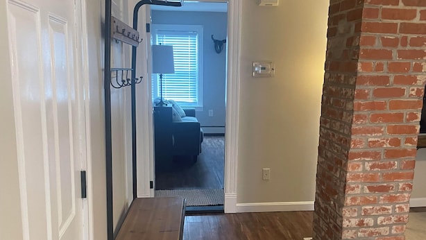 A hallway with a bench, a coat rack, and a door leading to a room with a window and a ceiling fan. - Entire rental unit in Warren, Rhode Island Unit 3 (Warren)