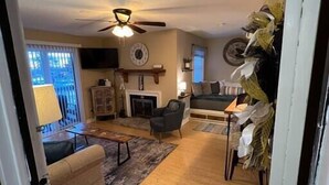 A living room with a fireplace, a ceiling fan, and a dining area with a table and chairs. - On Top Of Everything at Beech (Beech Mountain)