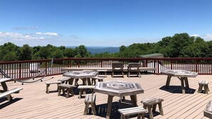 A wooden deck with picnic tables and chairs, overlooking a scenic landscape. - On Top Of Everything at Beech (Beech Mountain)