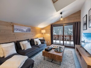 A cozy living room with a wooden interior, a sofa set, a coffee table, and a TV. - APARTMENT CHÂTEL - Les Freinets A202 (CHATEL)