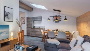 Un soggiorno moderno con divano, televisore, zona pranzo e cucina sullo sfondo.