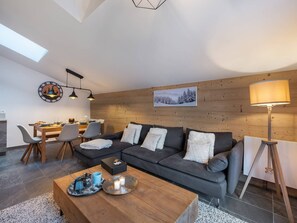 A modern living room with a sofa, coffee table, and dining area. - APARTMENT CHÂTEL - Les Freinets A202 (CHATEL)