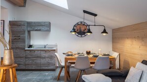 Una cucina moderna con un lucernario, una zona pranzo con tavolo e sedie in legno, e un'accogliente area salotto con un divano.