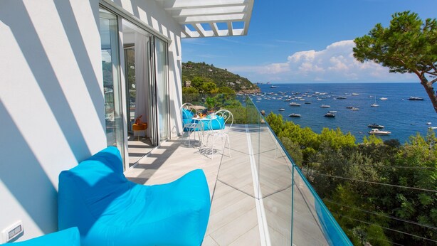 A balcony with a clear view of the sea, a white railing, and a blue sofa. - Villa Nerea - by Elite Villas (Massa Lubrense)