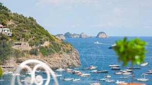 A coastal view with boats on the water, rocky cliffs, and buildings on the hillside. - Villa Nerea - by Elite Villas (Massa Lubrense)