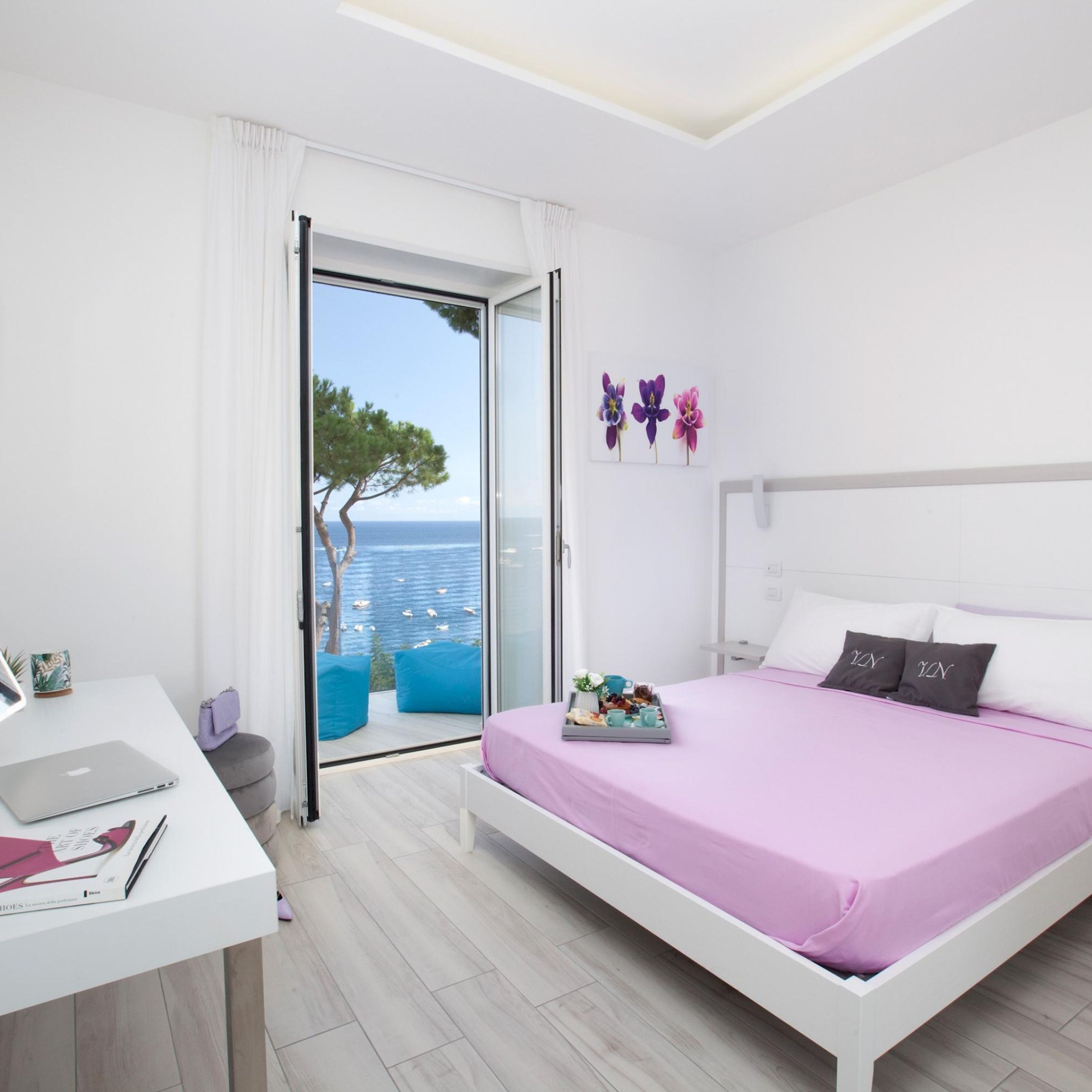 Une chambre moderne avec un lit, un bureau et une vue sur la mer.