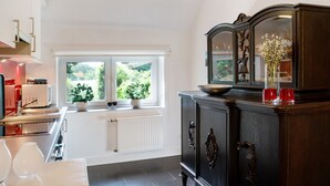 A modern kitchen with a window, a radiator, and a dark wooden cabinet.