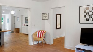 A modern living room with a television, a wicker chair, and a framed picture on the wall.