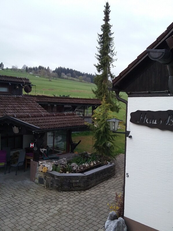 A rustic building with a sign reading 'Haus 15' and a large tree in front.