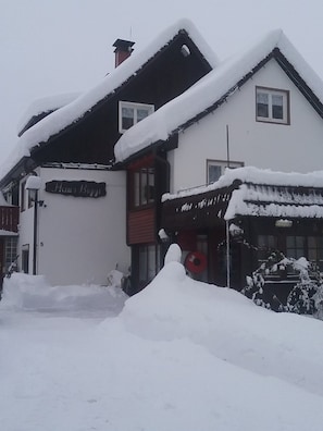 En snötäckt byggnad med en skylt där det står ”Hans Biggi”.