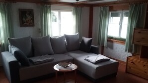 Una sala de estar con un sofá modular, una mesita de centro redonda y un aparador de madera.